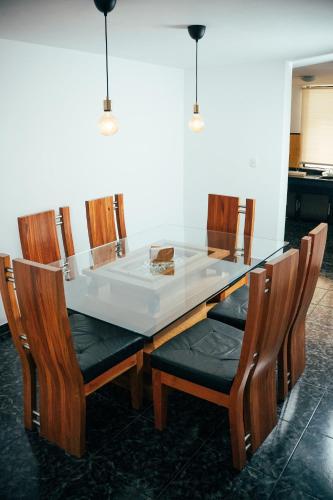 a dining table with a glass top and wooden chairs at Residenciales H1 & H2 - Breakfast & Room Service - Airport close in Santiago de los Caballeros