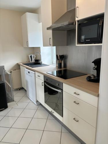 une cuisine avec des armoires blanches et un four à plaques de cuisson dans l'établissement Hebergement plaisant, à Gurgy