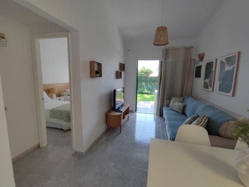 a living room with a blue couch and a television at Bungalow next Yumbo Center in Playa del Ingles
