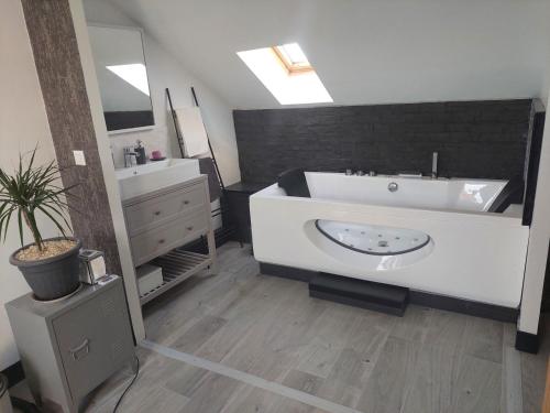 La salle de bains est pourvue d'une grande baignoire blanche et d'un lavabo. dans l'établissement Le Paradis de Sophie, au Havre
