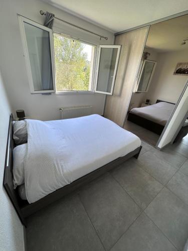 une chambre avec deux lits et deux fenêtres dans l'établissement Hameau de tranquillité, à Gap