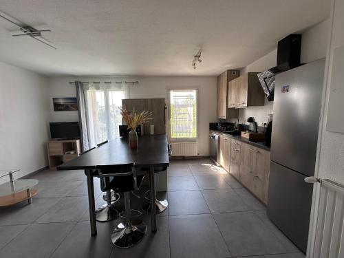 Il comprend une cuisine équipée d'une table noire et d'un réfrigérateur. dans l'établissement Hameau de tranquillité, à Gap