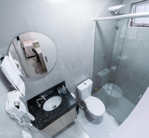 a bathroom with a sink and a toilet and a mirror at Flat Studio Alto Padrão em Patos de Minas in Patos de Minas