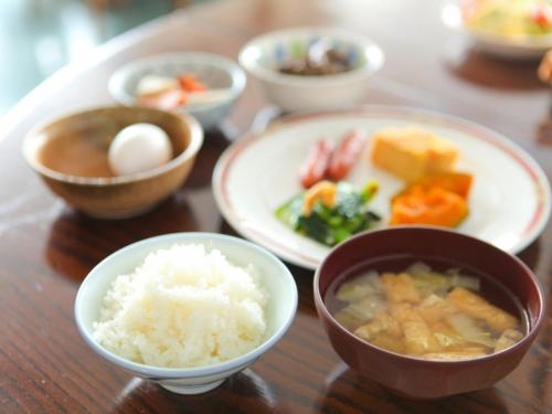 a wooden table topped with bowls of rice and vegetables at Terminal Art Inn - Vacation STAY 97366v in Niigata