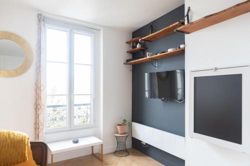 un salon avec un mur bleu et une télévision à écran plat dans l'établissement Cosy & quiet studio near La Villette, à Le Pré-Saint-Gervais