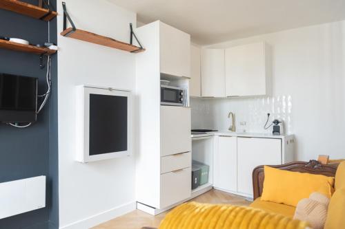 une cuisine avec des placards blancs et un canapé jaune dans l'établissement Cosy & quiet studio near La Villette, à Le Pré-Saint-Gervais