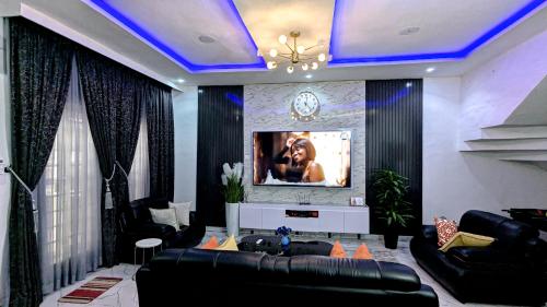 a living room with a couch and a tv on a wall at Amazing Shortlet in Lekki