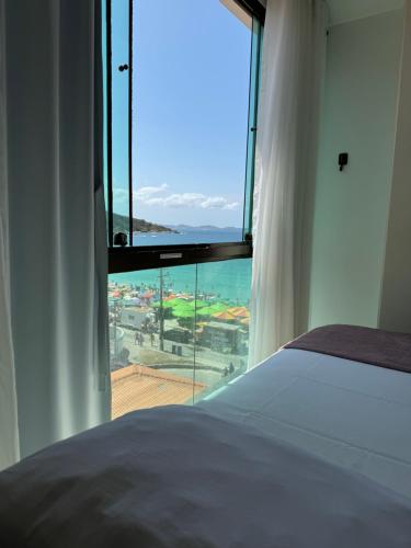 a bedroom with a large window with a view of the ocean at Loft Com Vista Para O Mar in Arraial do Cabo