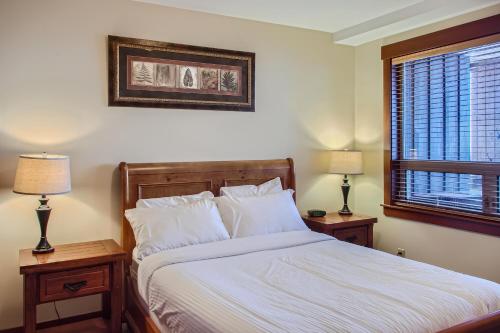 a bedroom with a bed with two nightstands and two lamps at Stonegate Resort Unit A202 in Big White