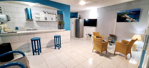 a kitchen with a counter and chairs and a refrigerator at Anse Maurice Évasion in Petit-Canal