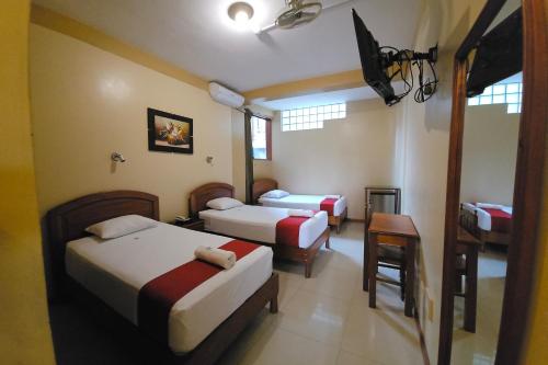 a room with two beds and a table and a chair at Hotel Centenario in Puerto Maldonado