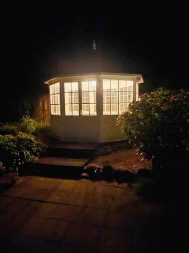 a house with a lit up window at night at Hyggeligt sommerhus med privat have in Brundbymark