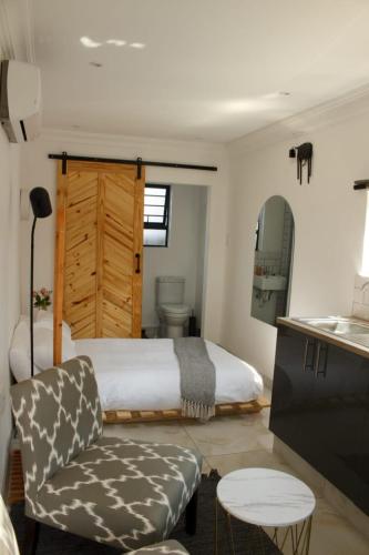 a bedroom with a bed and a chair and a table at Cozy Box Haus in Graskop