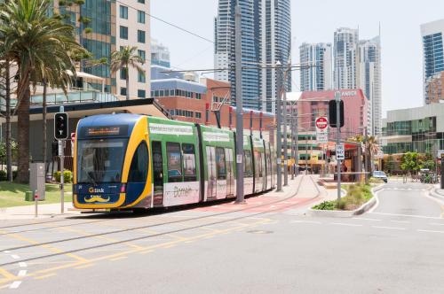 a yellow and blue tram on a city street at Costa D'Ora Holiday Apartments in Gold Coast