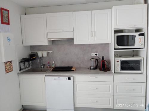 une cuisine blanche avec des armoires et des appareils blancs dans l'établissement Vacances Idéale en Bord de Mer, à Marseillan