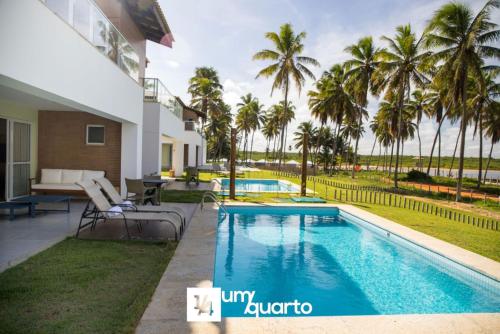 a villa with a swimming pool and palm trees at Ponta de Inhambupe Residences in Baixio