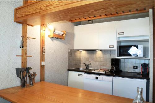 une cuisine avec des armoires blanches et un comptoir en bois dans l'établissement Résidence Le Cairn - studio 6 personnes le cairn N°705 MAE-6571, aux Orres