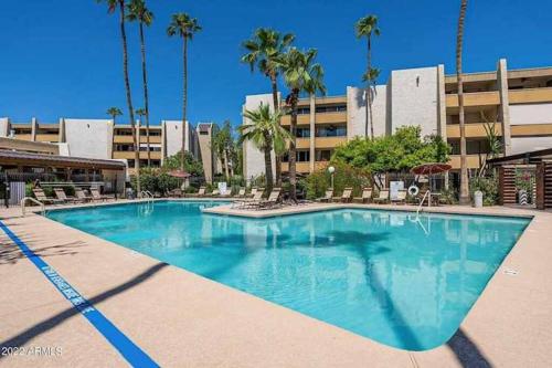 a swimming pool in front of a building with palm trees at Old Town Condo with 2 King Size Suites in Scottsdale