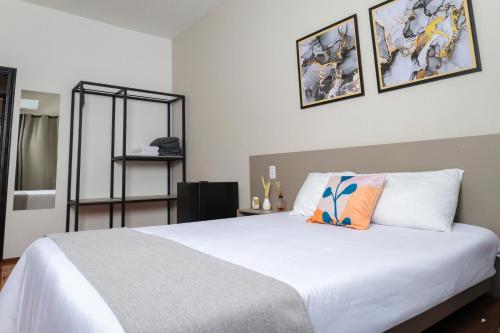 a bedroom with a white bed with two pictures on the wall at Smart Hotel in Guaxupé