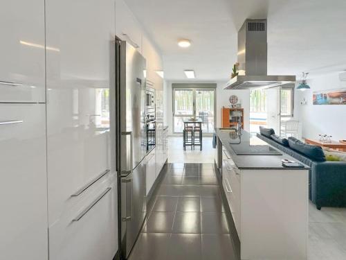 a kitchen with white cabinets and a blue couch at Apartamento con piscina privada in Alicante