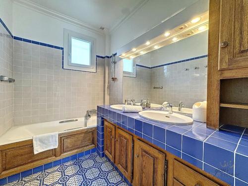 une salle de bain avec deux lavabos, une baignoire et un miroir dans l'établissement Villa Rosière, à Villers-sur-Mer