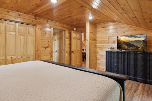 a bedroom with a bed in a room with wooden walls at The Cabin That Plays Hard & Rests Easy Black Bear Lodge in Pigeon Forge