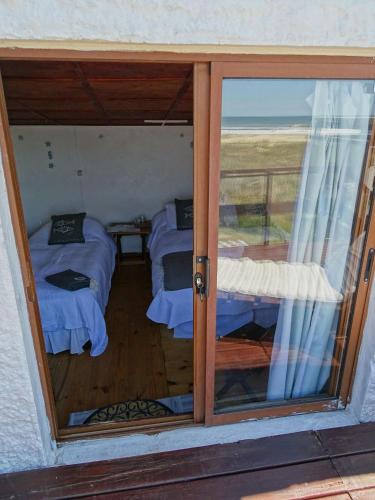 a room with two beds and a glass door at Carmela Suites Cabo Polonio in Cabo Polonio