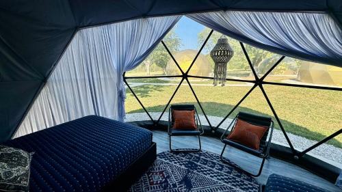a tent with two chairs and a bed and a window at DayDreamer Domes in South Haven