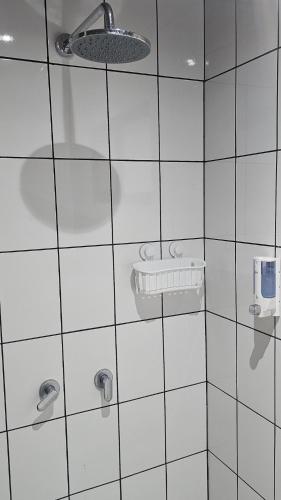 a white tiled bathroom with a sink and a light at El Castillo Harmony in El Castillo de La Fortuna