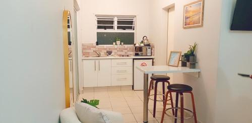 a small kitchen with two bar stools and a counter at Sea Breeze Manor - Aqua Unit in East London
