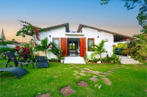 a house with a lawn and chairs in front of it at Casa paradise perto da praia Guarajuba - BA in Camacari