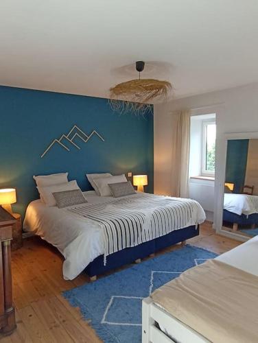 une chambre avec un grand lit avec un mur bleu dans l'établissement Les cimes de l'Oustal, à Ax-les-Thermes