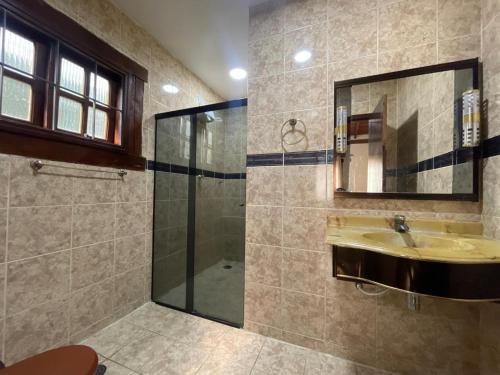 a bathroom with a shower and a sink and a mirror at FANTÁSTICA CASA COM ÁREA DE PISCINA até 10 PESSOAS em MARESIAS SÃO SEBASTIÃO in Maresias