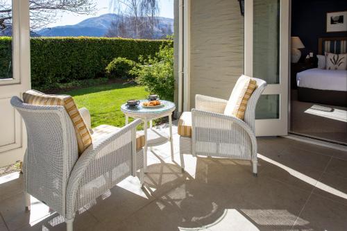 three wicker chairs and a table on a patio at Millbrook Resort in Arrowtown