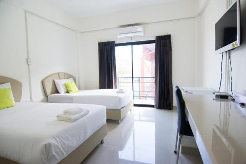 a hotel room with two beds and a television at Sunee Boutique Hotel in Uttaradit