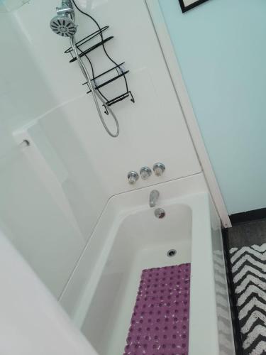 a bath tub with a purple mat in a room at Tower of Little Italy in Niagara Falls