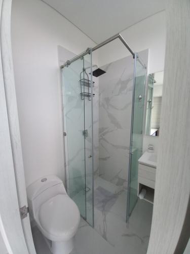a bathroom with a toilet and a glass shower at Playa y Relax comodidad junto al mar! in Santa Marta