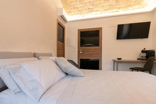 a bedroom with a white bed with a television on the wall at Le Fantine Rooms in Campomarino