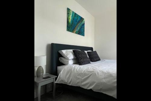 ein Schlafzimmer mit einem Bett und einem Gemälde an der Wand in der Unterkunft Centrally located, beautifully presented apartment in Torquay
