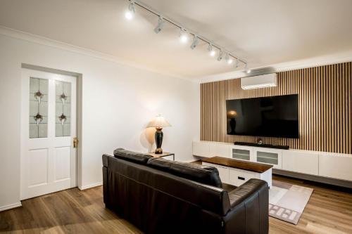 a living room with a couch and a flat screen tv at The Driscoll - Modern Smart Villa in West Tamworth