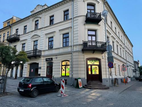 samochód zaparkowany przed dużym budynkiem w obiekcie Apartamenty Łuczkowskiego z widokiem na Studnię 3 w mieście Chełm