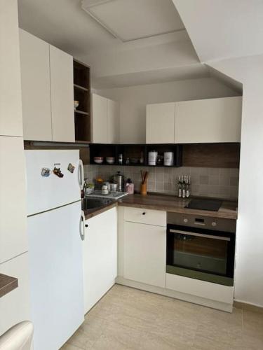 una cucina con mobili bianchi e un frigorifero bianco di Spring apartment a Skopje