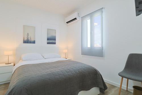 a white bedroom with a bed and a window at R&M Place in São Roque