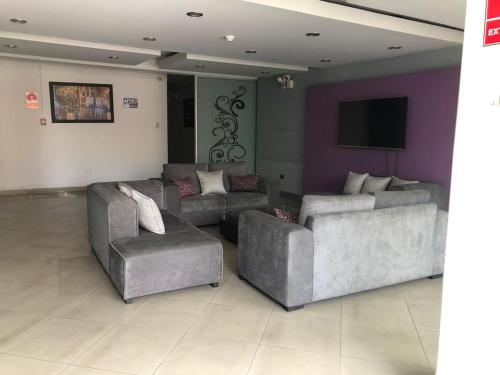 a living room with two couches and a flat screen tv at Gran Hotel Victoria in Tacna