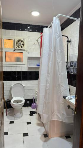 a bathroom with a toilet and a shower curtain at Atheers apartment in Madinaty