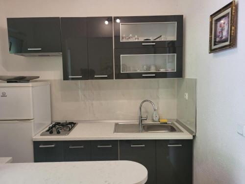 a kitchen with black cabinets and a sink and a refrigerator at Apartments Villa Smokvina in Bogomolje