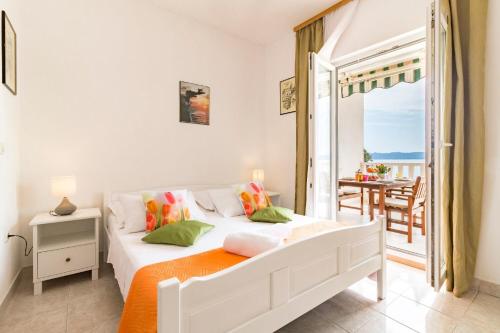 a white bedroom with a bed and a balcony at Apartments Villa Smokvina in Bogomolje