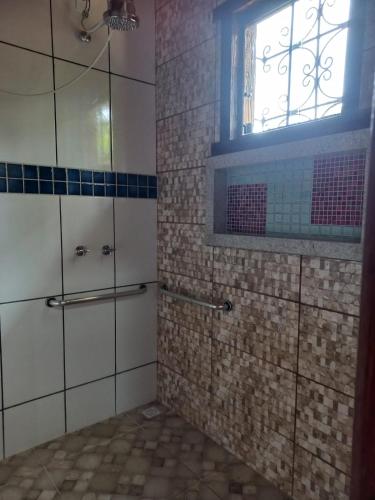 a bathroom with a shower with a window and tiles at Pousada Cachoeiras do Cipó in Serra do Cipo