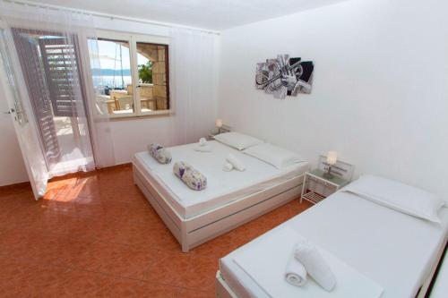 ein weißes Zimmer mit zwei Betten und einem Fenster in der Unterkunft Apartments and Rooms Hope in Brela