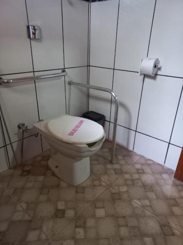 a bathroom with a toilet with a sign on it at Pousada Cachoeiras do Cipó in Serra do Cipo